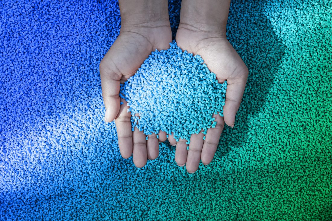 Mani che raccolgono granuli di plastica riciclata